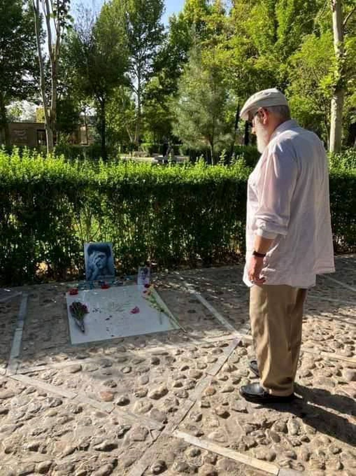 تصویری جالب از علی‌اکبر ناطق نوری با لباس شخصی بر مزار محمدرضا شجریان